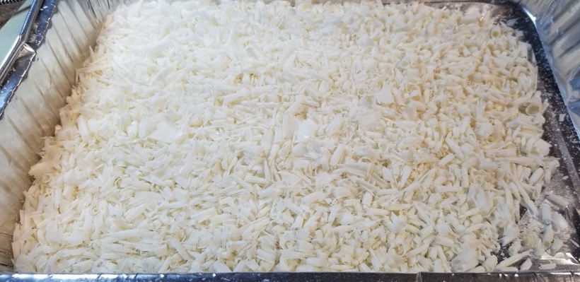 A photograph of a disposable cake tin full of white, curled up peels of soap.