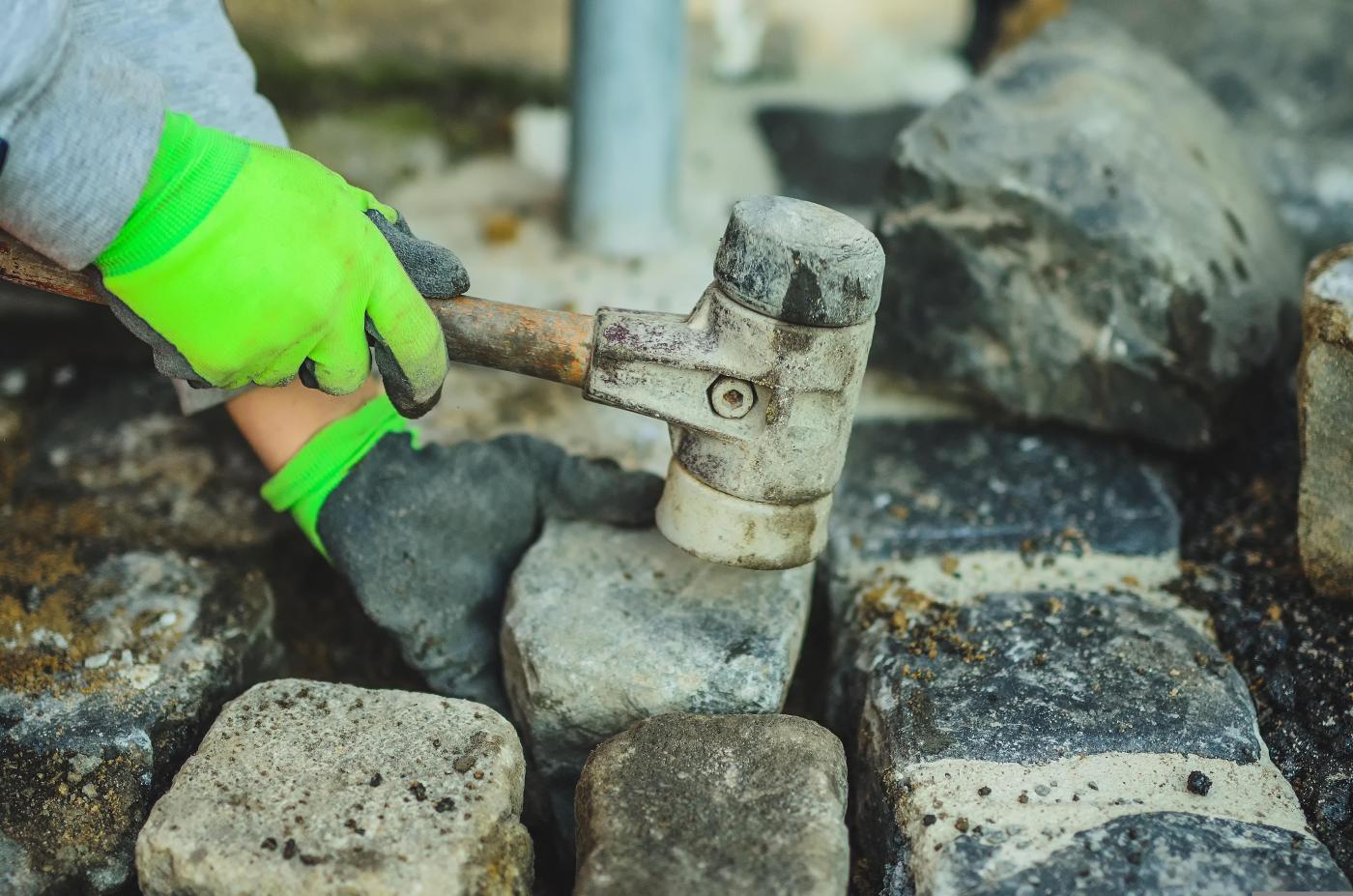 Photograph of a person hammering a cobblestone into place.
