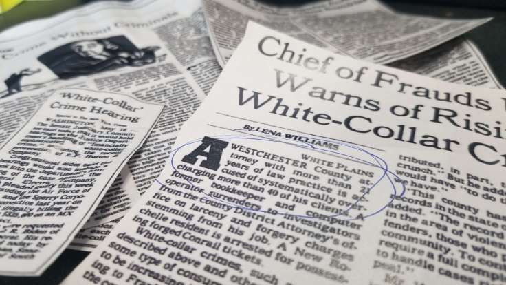 Close-up photograph of several articles printed on newsprint, the top of which has a circled hint