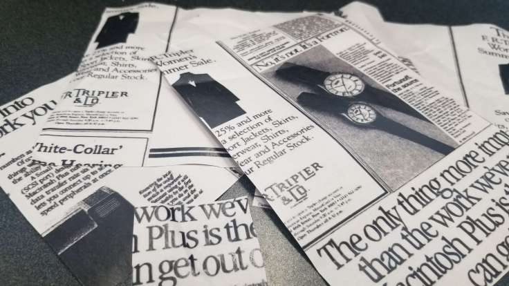 Close-up photograph of back side of articles printed on newsprint, with advertisements from 1986.