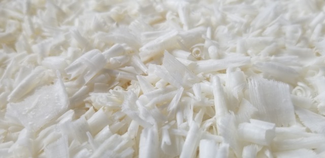 Close up photograph of white Nabulsi soap, scraped into curls -- the curls look like white chocolate shavings.